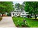 Charming two-story home with white painted brick, gray shutters, mature trees, long driveway, and a lush front yard at 433 Rosehaven Dr, Raleigh, NC 27609