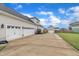 Detached garages with ample parking on a concrete driveway, enhanced by lush landscaping and blue skies at 450 S Parliament Way, Clayton, NC 27520