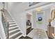 Bright foyer featuring wood-look flooring, a staircase with wooden handrail, and views into an adjacent home office at 450 S Parliament Way, Clayton, NC 27520