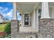 Inviting front porch with stone supports, a welcoming wreath, and decorative plants create a cozy and appealing entrance at 450 S Parliament Way, Clayton, NC 27520