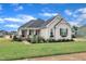 Charming home features a welcoming front porch, stone accents, and professionally landscaped yard with mature plantings at 450 S Parliament Way, Clayton, NC 27520