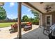 Covered patio area with wicker seating, barbecue, and view of the green, spacious backyard at 4621 Basilica Dr, Holly Springs, NC 27540