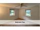 Bedroom features neutral carpet, two windows for natural light, and a ceiling fan at 4720 Rivermont Rd, Durham, NC 27712