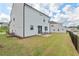 A spacious backyard featuring a grassy lawn and a patio area with outdoor seating and a white siding home at 509 Rain Drizzle Ct, Wake Forest, NC 27587