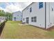 Well-maintained backyard with a grassy lawn, a small patio area with outdoor seating, and a white siding home at 509 Rain Drizzle Ct, Wake Forest, NC 27587