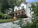 Side angle view of a two-story white farmhouse featuring a lush yard and a welcoming front porch at 517 Bart St, Raleigh, NC 27610