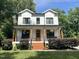 Charming two-story white farmhouse with inviting front porch, beautiful landscaping, and updated windows at 517 Bart St, Raleigh, NC 27610