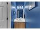 Stylish half bathroom with a single sink vanity, modern fixtures, and vibrant blue walls at 5603 Whisperwood Dr, Durham, NC 27713