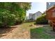 Large backyard featuring a fire pit, green grass, and mature trees at 6004 Solitude Way, Durham, NC 27713