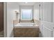 Relaxing bathroom showcasing a tiled soaking tub with a window for natural light at 640 Barneswyck Dr, Fuquay Varina, NC 27526