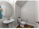 Well-lit half bathroom with a pedestal sink, toilet, and wood-look flooring at 640 Barneswyck Dr, Fuquay Varina, NC 27526