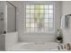 Close-up on a soaking tub with a patterned glass window and a shower at 705 Harkness Cir, Durham, NC 27705