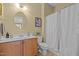Well-lit bathroom featuring a wooden vanity, decorative mirror, and a shower with a white patterned curtain at 705 Harkness Cir, Durham, NC 27705