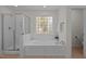 Bright bathroom featuring a shower, soaking tub, and patterned glass window at 705 Harkness Cir, Durham, NC 27705