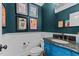 Stylish powder room with a decorative vanity, dark teal walls, and unique artwork at 763 Heritage Arbor Dr, Wake Forest, NC 27587