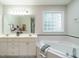Elegant bathroom featuring double sinks, a soaking tub, and a glass-block window at 9020 Branch Creek Way, Apex, NC 27539