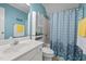 Bright bathroom with a blue shower curtain, white cabinets and a vanity at 907 Stuart Dr, Mebane, NC 27302