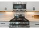 Modern kitchen features stainless steel gas range, microwave, subway tile, and white cabinets at 100 Emory Bluffs Dr, Holly Springs, NC 27540