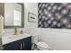 Stylish powder room with unique wallpaper, navy vanity, and modern fixtures at 100 Emory Bluffs Dr, Holly Springs, NC 27540