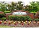 Inviting brick Magnolia Creek entrance sign with manicured landscaping and colorful flower beds on a sunny day at 1004 Summer Mist Ln, Durham, NC 27704