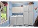 Functional laundry room with washer, dryer, ample cabinet storage, and stylish blue and white tile flooring at 104 Cedar Ridge Way, Durham, NC 27705