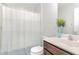 Cozy bathroom with a shower-tub combo featuring blue-striped curtains and vanity with vase of flowers at 1138 Bexley Hills Bnd, Apex, NC 27502