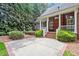 Charming brick home with a covered porch and concrete patio; surrounded by mature trees and lush landscaping at 122 Barringer Dr, Garner, NC 27529