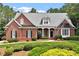 Charming brick home with a manicured lawn, lush landscaping, and covered front porch at 122 Barringer Dr, Garner, NC 27529