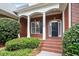Inviting brick porch with white columns and black door, surrounded by manicured landscaping at 122 Barringer Dr, Garner, NC 27529