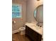 Chic powder room with dark vanity, stone countertop, round mirror, and textured wallpaper at 1300 Seabrook Ave, Cary, NC 27511