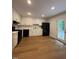 White kitchen featuring an black appliance suite, modern cabinets, and warm wood flooring at 1300 Seabrook Ave, Cary, NC 27511
