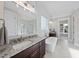 Modern bathroom showcasing a freestanding tub, dark wood vanity, large mirrors, and a glass-enclosed shower at 1325 Mackinaw Dr, Wake Forest, NC 27587