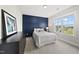 Comfortable bedroom featuring a stylish accent wall, plush bedding, and a bright window with neighborhood scenery at 1325 Mackinaw Dr, Wake Forest, NC 27587