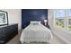 Inviting bedroom features a blue accent wall, soft bedding, a side table with lamp, and a window view at 1325 Mackinaw Dr, Wake Forest, NC 27587