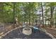 Outdoor brick fire pit in a wooded backyard setting, complete with charming blue-cushioned chairs at 1325 Mackinaw Dr, Wake Forest, NC 27587