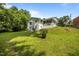 Spacious backyard with mature trees and a white brick house at 1713 Elder Ct, Burlington, NC 27215