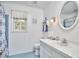 Bright bathroom featuring blue tiled floors, white fixtures, oval mirror and window at 1913 Fawndale Dr, Raleigh, NC 27612
