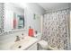 Well-lit bathroom featuring a single vanity, a decorative mirror, and a shower/tub with a patterned curtain at 213 Bracken Ct, Raleigh, NC 27615