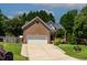 Charming brick home with a two-car garage, manicured lawn, and mature trees creating a welcoming curb appeal at 2302 Fordcrest Dr, Apex, NC 27502