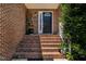 Inviting front porch with brick stairs, decorative plants, and a classic black front door at 2302 Fordcrest Dr, Apex, NC 27502