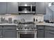 Modern kitchen features stainless steel appliances, granite countertops, and stylish gray cabinetry at 2302 Fordcrest Dr, Apex, NC 27502