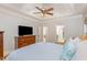 View of the main bedroom features a ceiling fan and wood dresser with a TV in a well-lit space at 240 Oak Grove Church Rd, Youngsville, NC 27596
