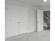 Spacious bedroom with a large closet and view to wooden stairs, neutral walls and plush carpeting throughout at 2539 Kasota Ln, Raleigh, NC 27610