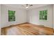 Bedroom with hardwood floors and two windows overlooking lush greenery at 3006 Pump Station Ln, Durham, NC 27712