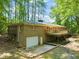 Rear exterior view of a brick house with a garage, deck, and lush greenery at 3006 Pump Station Ln, Durham, NC 27712
