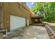 Back exterior of a brick house with garage, deck, and wooded surroundings at 3006 Pump Station Ln, Durham, NC 27712