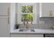 Close up of the kitchen sink and window featuring gold fixtures and decorative backsplash at 308 Greenwood Dr, Durham, NC 27704