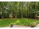 Landscaped backyard boasts a grassy area with mature trees and outdoor patio space, perfect for entertaining at 317 Chanticlair Dr, Apex, NC 27502