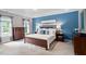 Bright bedroom features a blue accent wall, wood furniture and natural light from windows with neutral curtains at 317 Chanticlair Dr, Apex, NC 27502