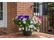 Close-up of a colorful flower pot on a brick porch with an iron railing at 317 Chanticlair Dr, Apex, NC 27502